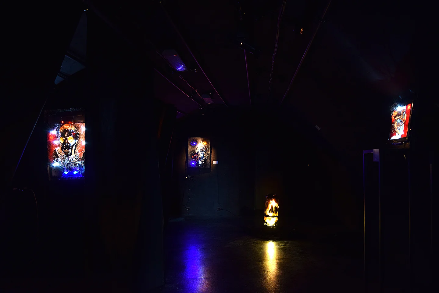 Deus Ex Machina — backlit works glowing in a darkened exhibition space