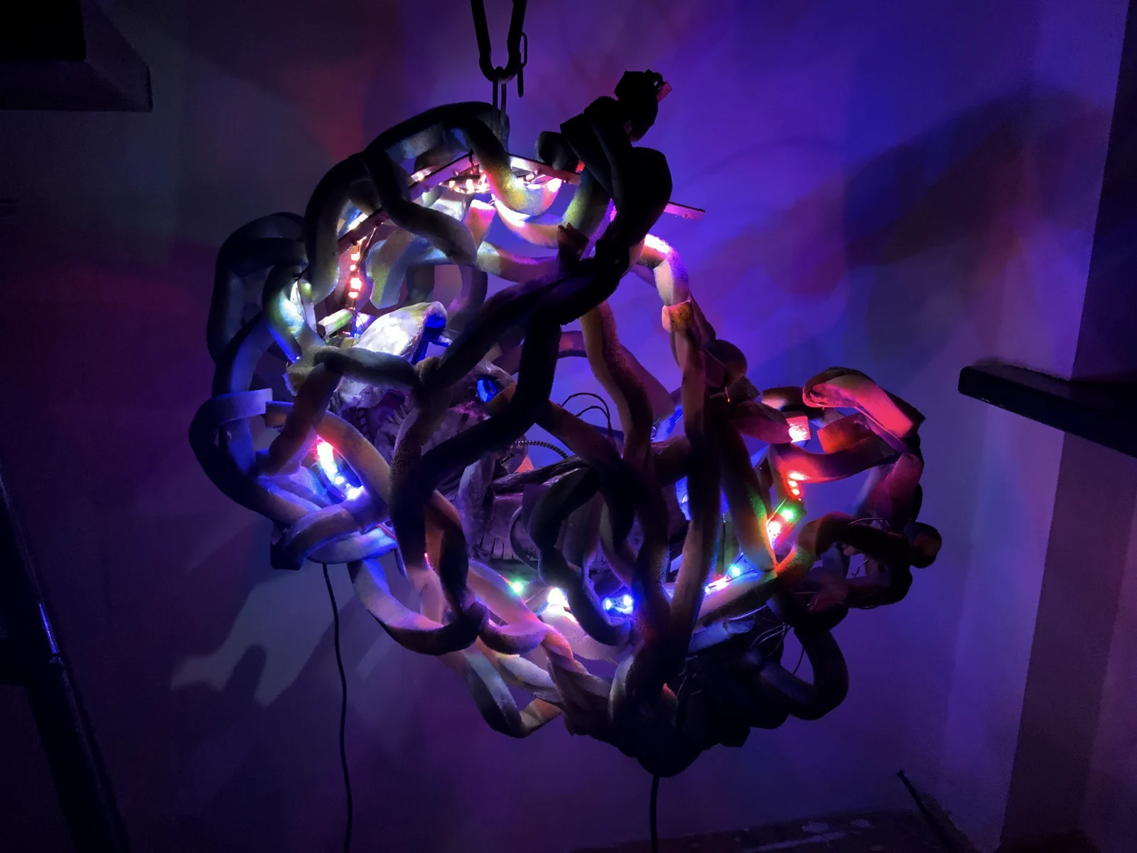 Baby Ghost — a suspended tangle of pale limbs and coloured LEDs glowing in the dark