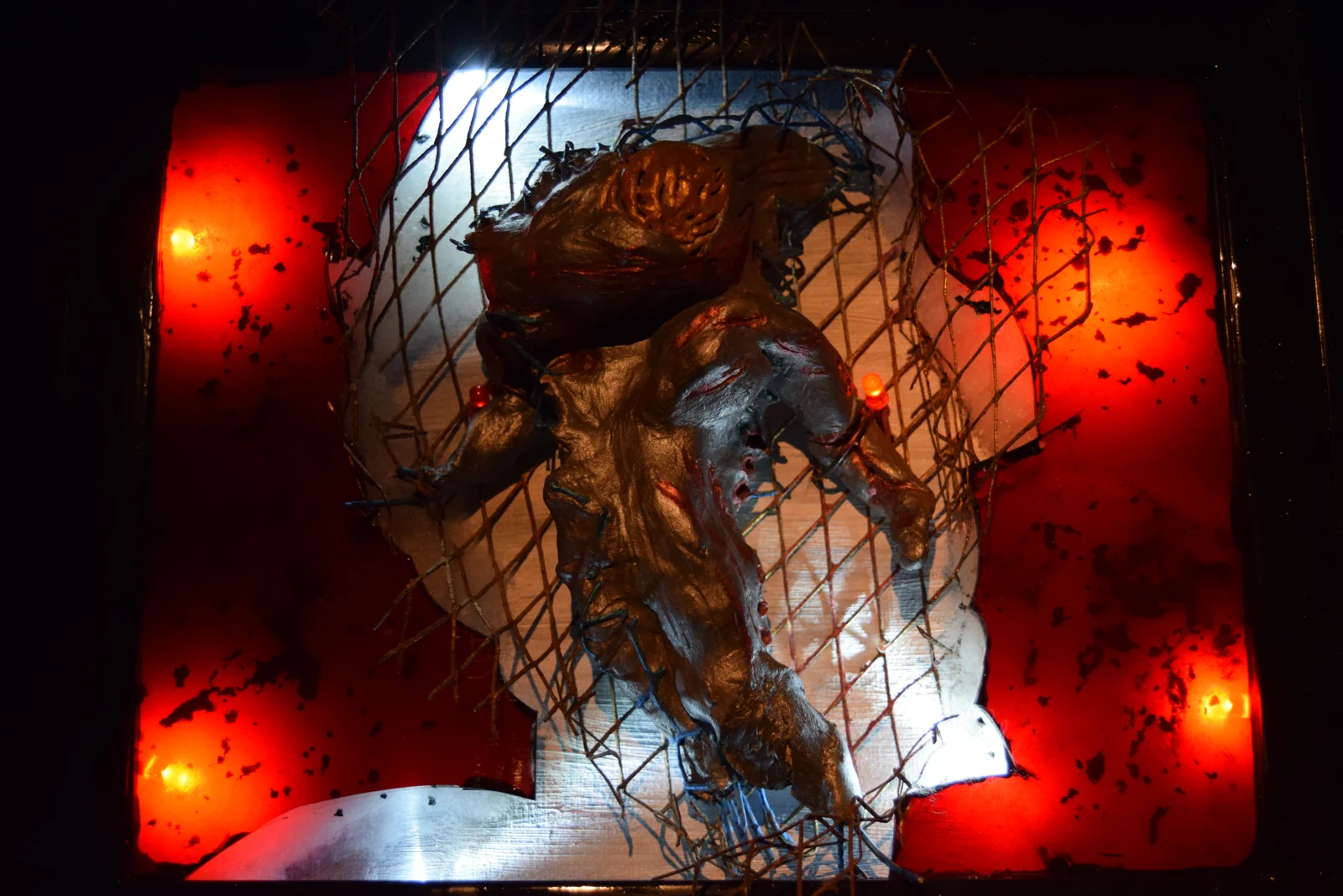 Machinarium — a metallic figure caged behind wire mesh against glowing red panels