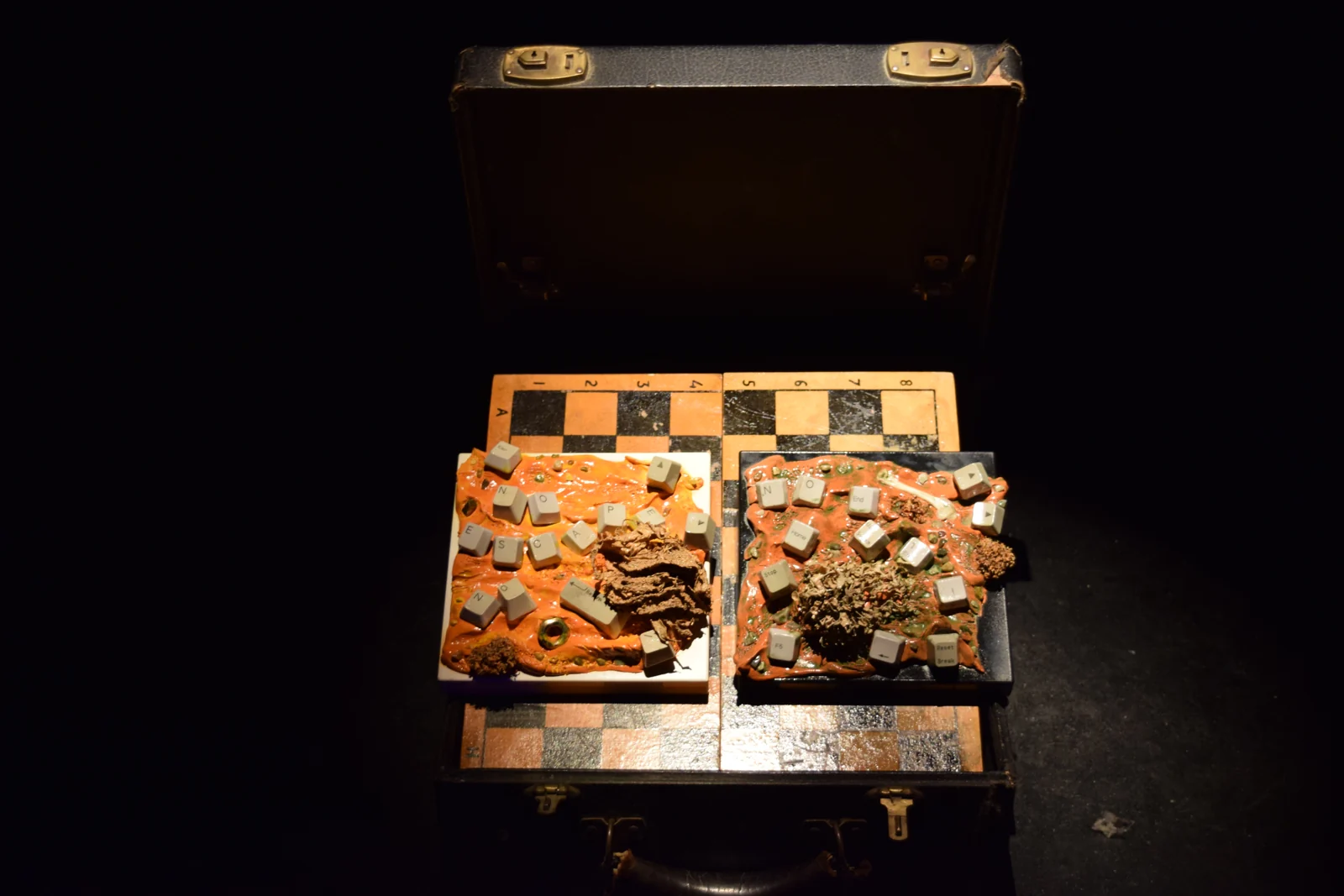Machinarium — an open case holding two chessboards encrusted with keyboard keys and debris