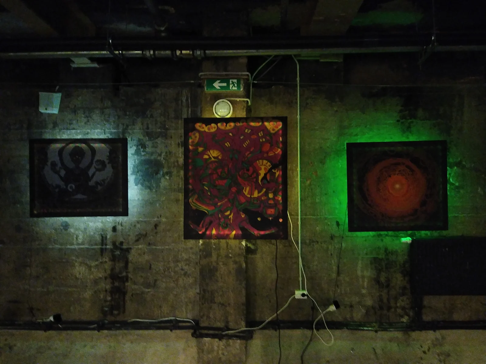 Nine Doors to Perception — three artworks lit in blue, purple and green on a concrete wall